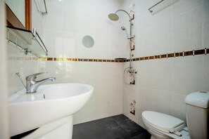 Une salle de bain avec un lavabo blanc, des toilettes et une douche.