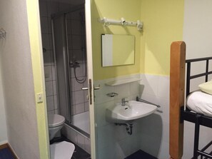 A small bathroom with a shower, toilet, sink, and a mirror.