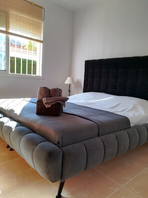 Une chambre à coucher avec un grand lit, une lampe de chevet et une fenêtre avec des stores.