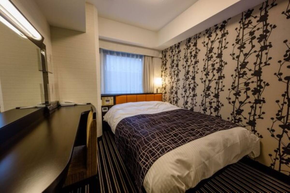 A hotel room with a bed, a desk, and a nightstand.