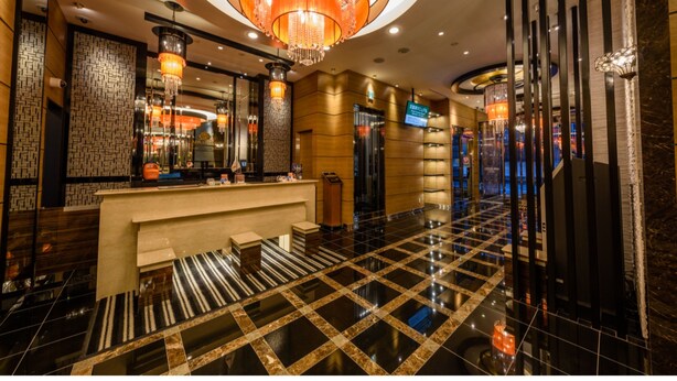 Een hotel lobby met een receptiebalie, een grote kroonluchter en een incheckbalie.