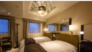 Een hotelkamer met een groot bed, een bureau, een stoel, een staande lamp en een spiegel.
