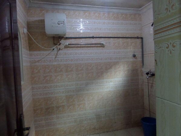 A bathroom with patterned tiles, a towel rack, a toilet, and a blue trash bin.