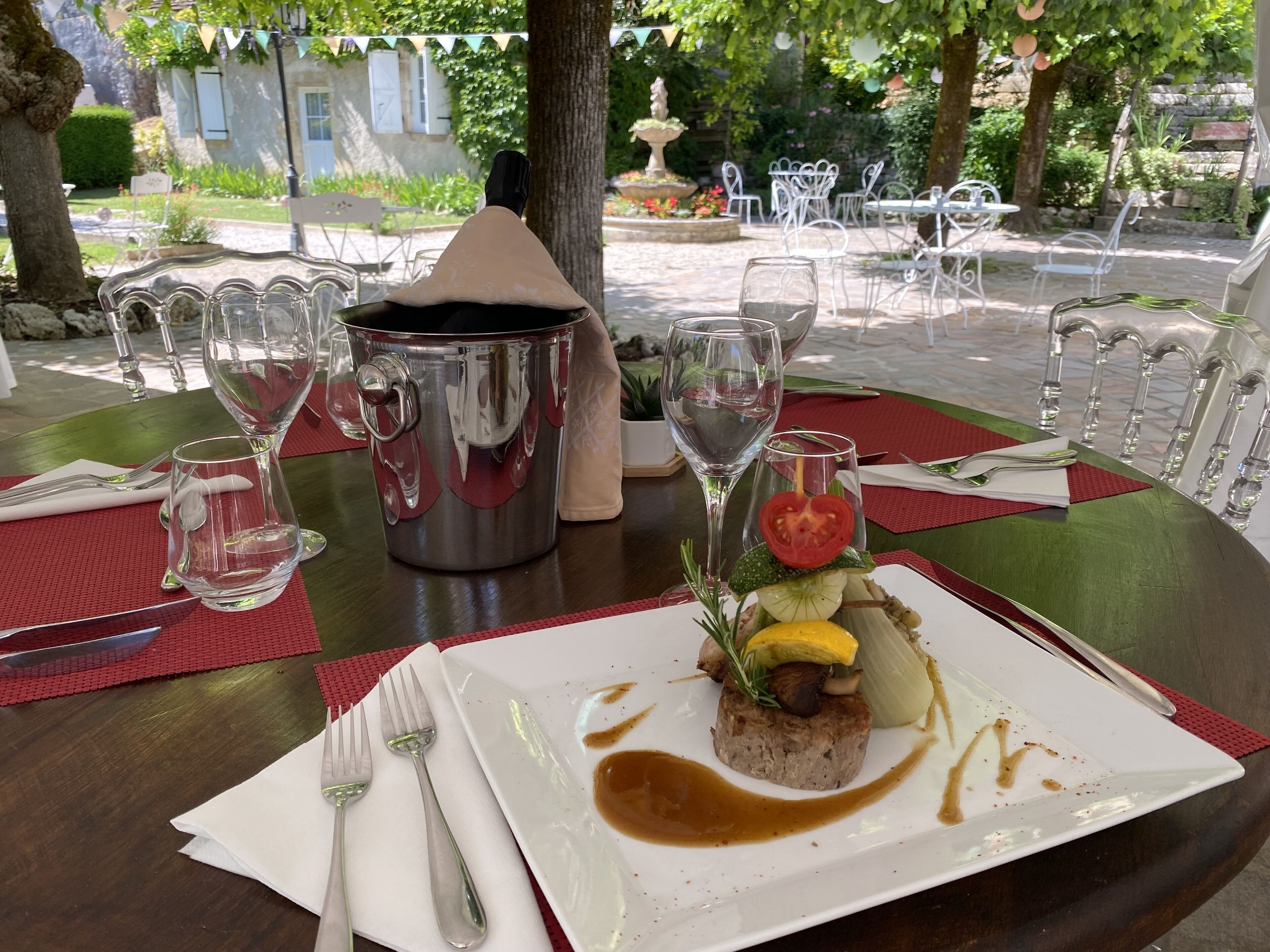 Mesa de comedor al aire libre con comida, copas de vino y una olla de metal.