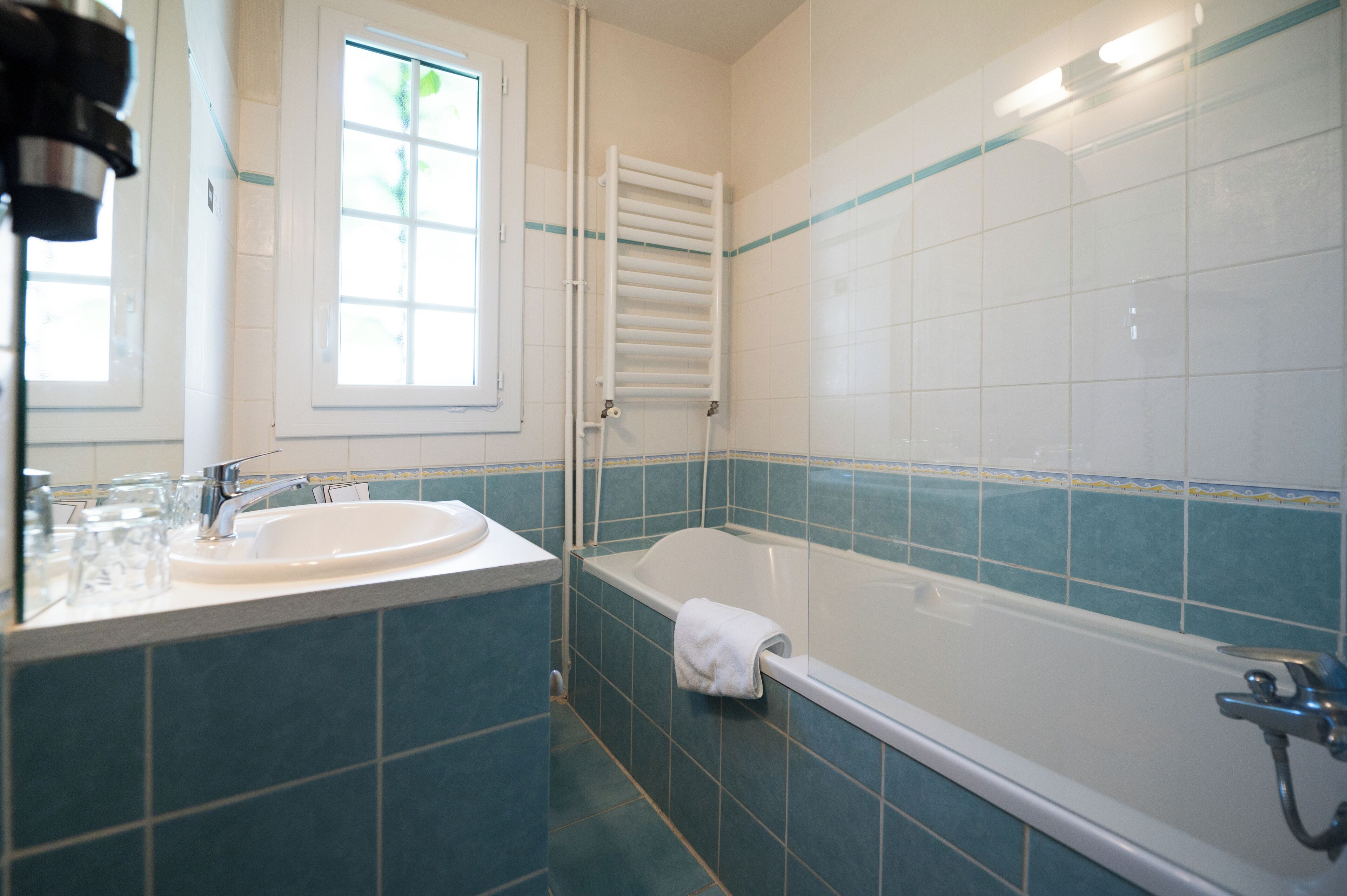 A bathroom with a sink, mirror, window, and bathtub.