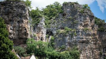 Eine steile Klippe mit natürlichen Felsformationen und einem kleinen Gebäude am Fuße.