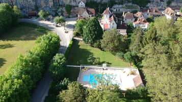 An aerial view of a residential area with houses, a road, and a swimming pool.