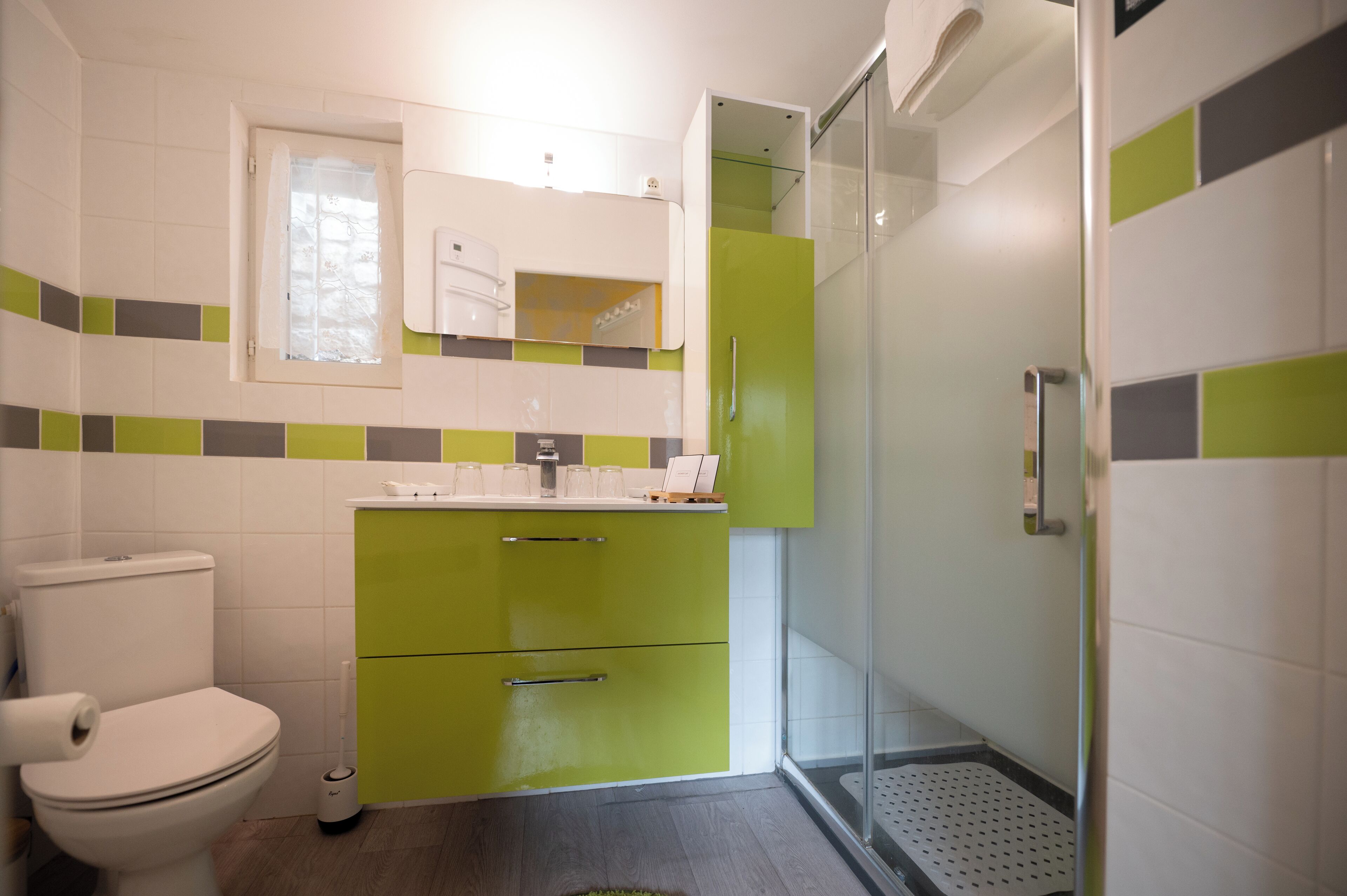 A bathroom with a toilet, a sink, a mirror, and a shower area.