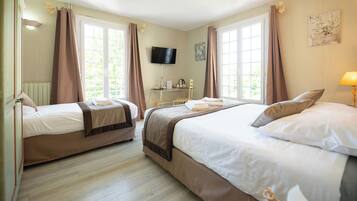 Habitación de hotel con dos camas, televisión, escritorio con silla y ventanas amplias con cortinas.