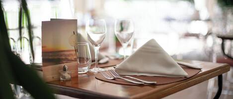 A dining table set with a menu, wine glasses, and cutlery.