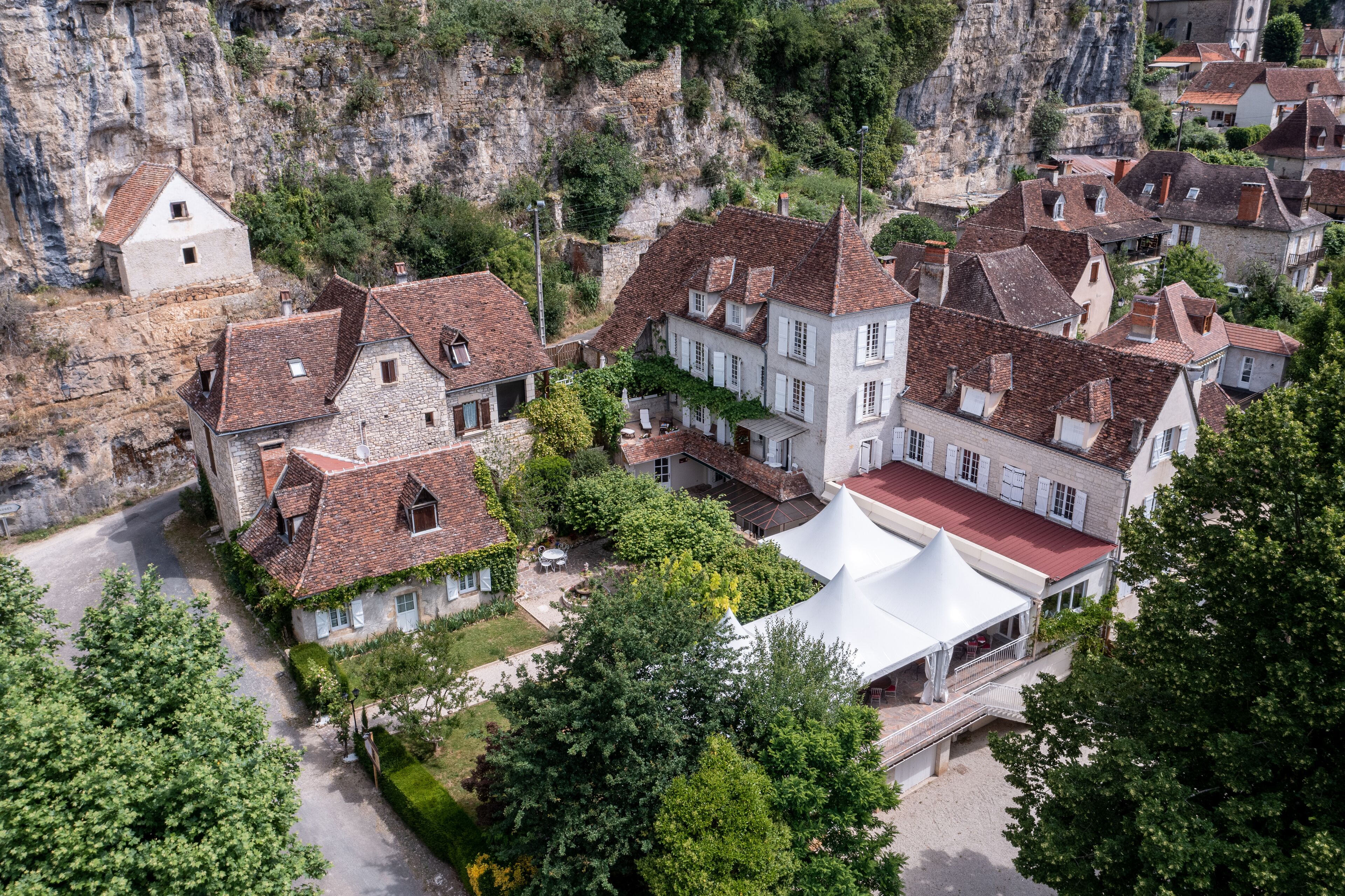 A traditional European village with stone buildings, a white tent structure, and lush greenery.
