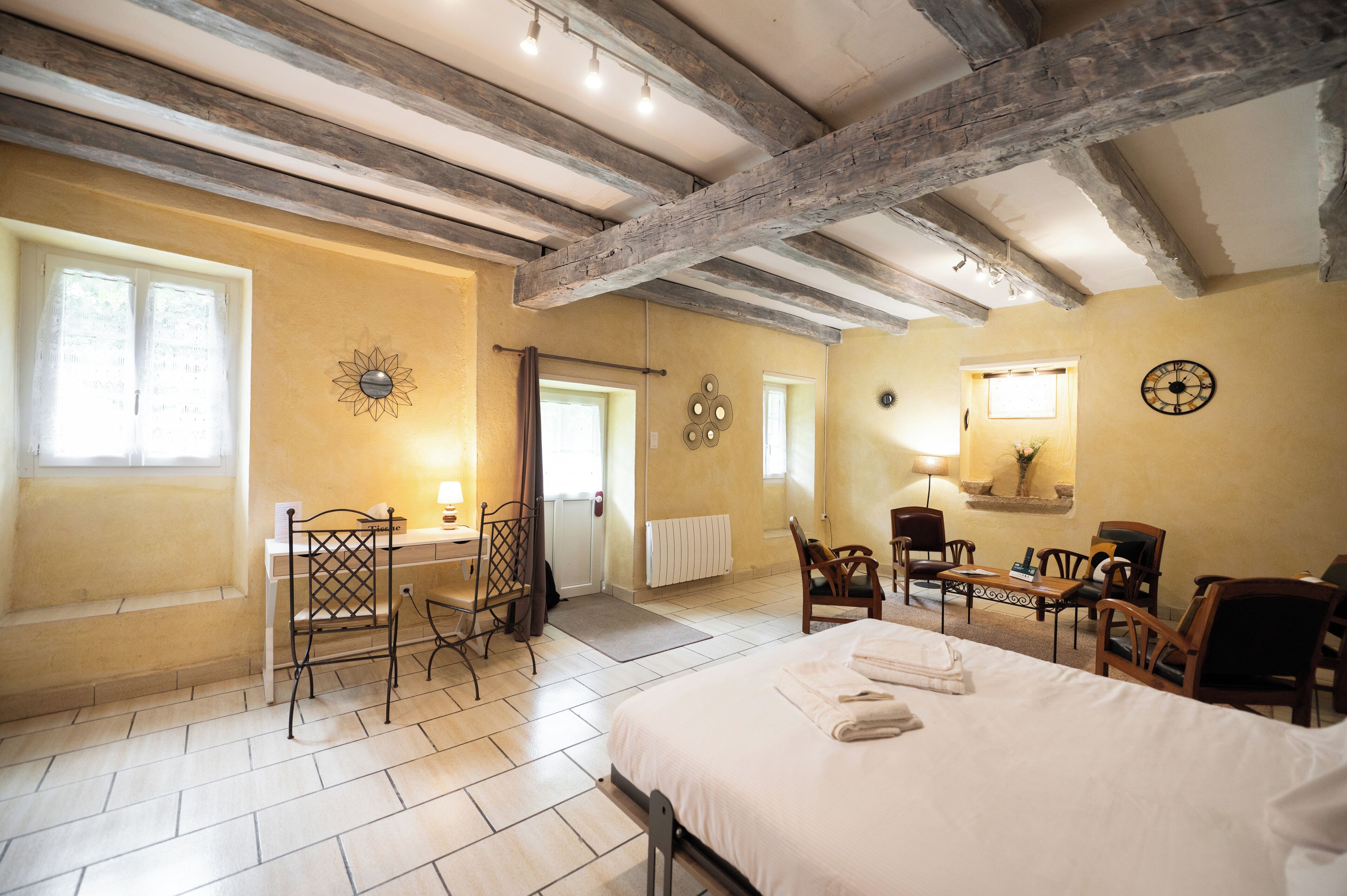 Une chambre d’hôtel comprenant un lit, un bureau et un coin salon avec des chaises.