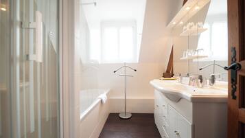 A modern bathroom with a bathtub, a large mirror, and a vanity with a sink.