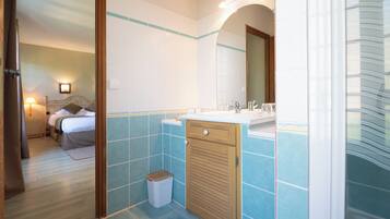 Un baño con lavamanos, espejo y paredes con azulejos.