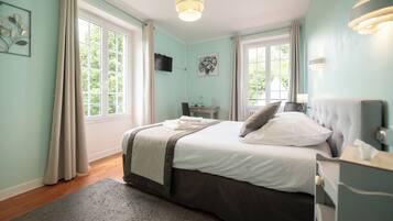 A bedroom with a bed, bedside table, lamp, and a window with curtains.