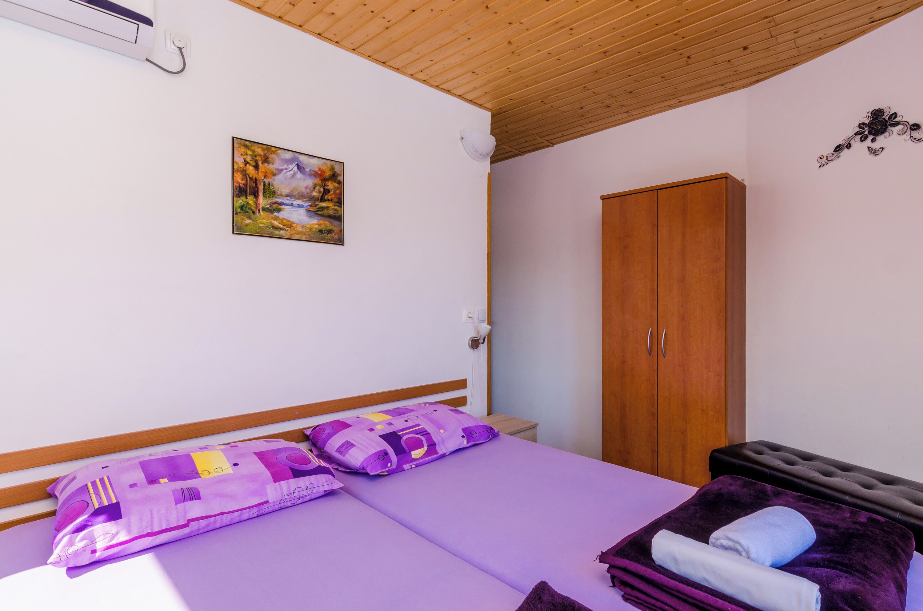 Un dormitorio con cama, un armario de madera, un cuadro en la pared y un ventilador de techo.