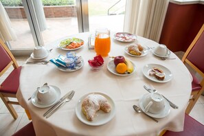 Una mesa de desayuno con platos de comida, una jarra de jugo de naranja y teteras.
