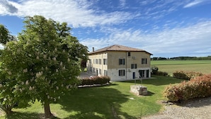 A two-story building with a tiled roof, surrounded by a well-maintained lawn and a gravel driveway. - Corte Galvana (Cento)