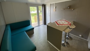 A modern kitchen with a teal bench, a small island with a table, and a sliding glass door leading to a balcony. - Corte Galvana (Cento)