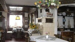 A dining area with a table set for two, a hanging floral arrangement, and a view of the kitchen in the background. - Pension Schlossbergblick (Simonswald)