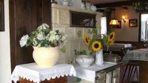 A kitchen with a white countertop, a wooden cabinet, and a vase with flowers. - Pension Schlossbergblick (Simonswald)