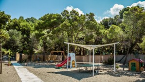 A sandy play area with a slide, a small playhouse, and a picnic table. - Villaggio Residence Torre Saracena - Campsite (Camerota)