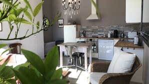 A compact kitchen with a dining area, a chandelier, and a wicker chair. - La Pénesais (Beaumont-en-Veron)