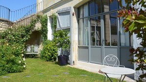 A building with a stone facade, large windows, and a small garden with a bench and a table. - La Pénesais (Beaumont-en-Veron)