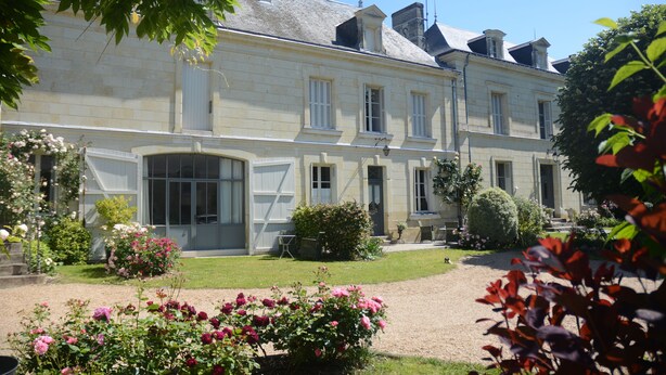 A large, historic building with a symmetrical facade, multiple windows, and a well-maintained garden with flowering plants. - La Pénesais (Beaumont-en-Veron)