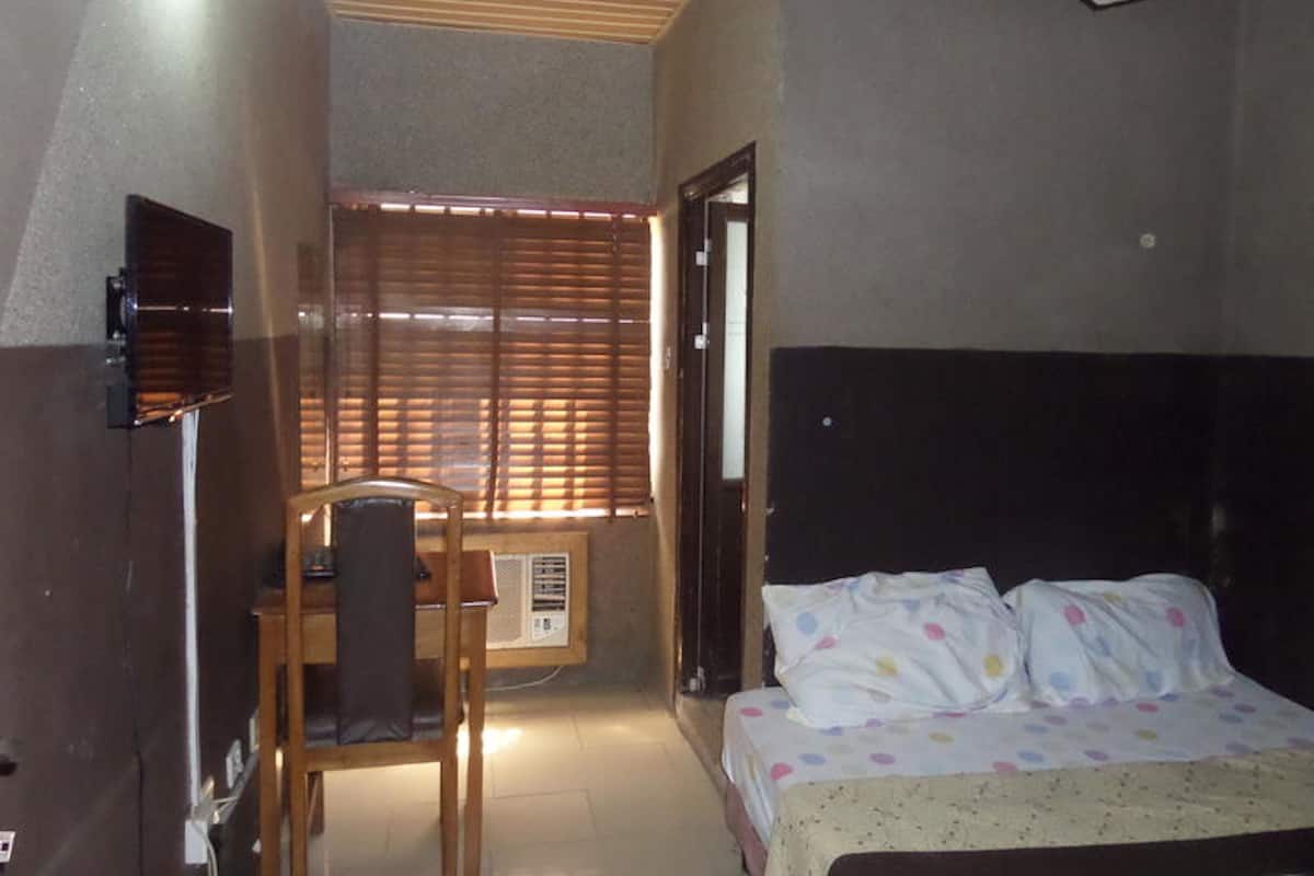 A bedroom with a bed, a desk, and a chair.