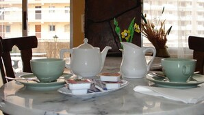 A table set with a white teapot, two green cups, and a tray with food items. - Pensión el Hidalgo (Calpe)