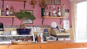 A kitchen with wooden chairs, a bar counter, and various kitchen items. - Pensión el Hidalgo (Calpe)