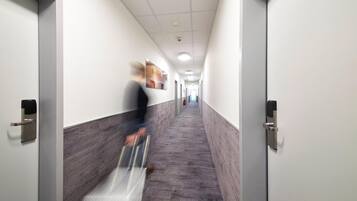 Ein modern gestalteter Flur mit heller Decke, Wandmuster und einer langen Korridor mit Türen an beiden Seiten.