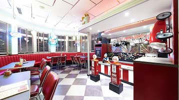 A diner with red booths and tables, a jukebox, and a neon sign.