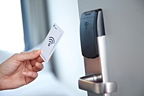 A hand holding a card near a door with a card reader.