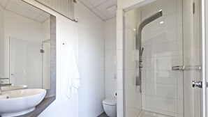Un baño moderno con un lavamanos grande, inodoro y ducha a ras de suelo.