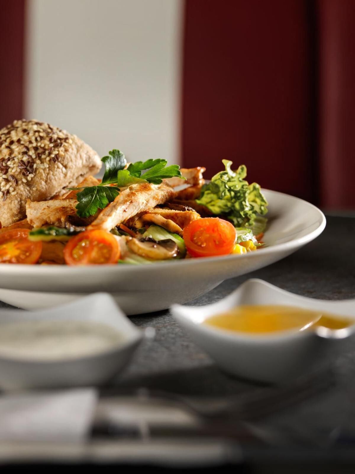A plate of food with a slice of grilled chicken, a slice of bread, and a side salad.