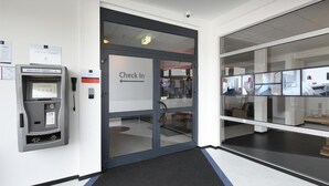 Un espace d’accueil d’hôtel comprenant un comptoir de réception, un guichet d’enregistrement et une caméra de surveillance.