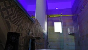 Ein Badezimmer im modernen Design mit einer großzügigen Badewanne, einer Duschkabine aus Glas und Wandfliesen mit Muster.
