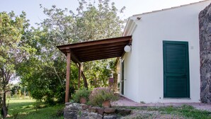 Valkoinen rakennus, jossa on kiviseinä ja puinen pergola.