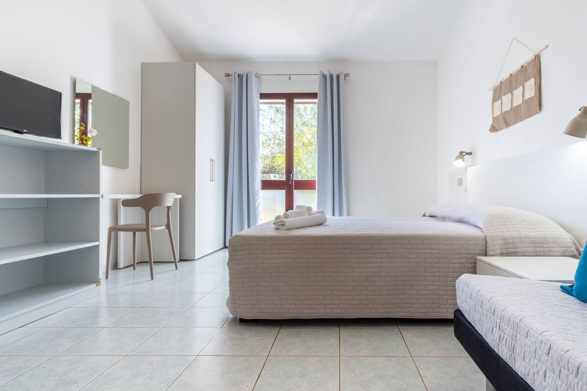 A modern bedroom with a large bed, a desk, and a chair.