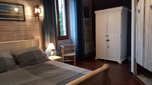 A bedroom with a bed, a nightstand with a lamp, a chair, and a wardrobe. - La Palombiere (Lucmau)
