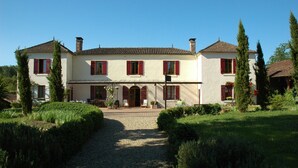 A large, two-story house with a symmetrical facade, multiple windows with shutters, and a central entrance with a door. - La Palombiere (Lucmau)