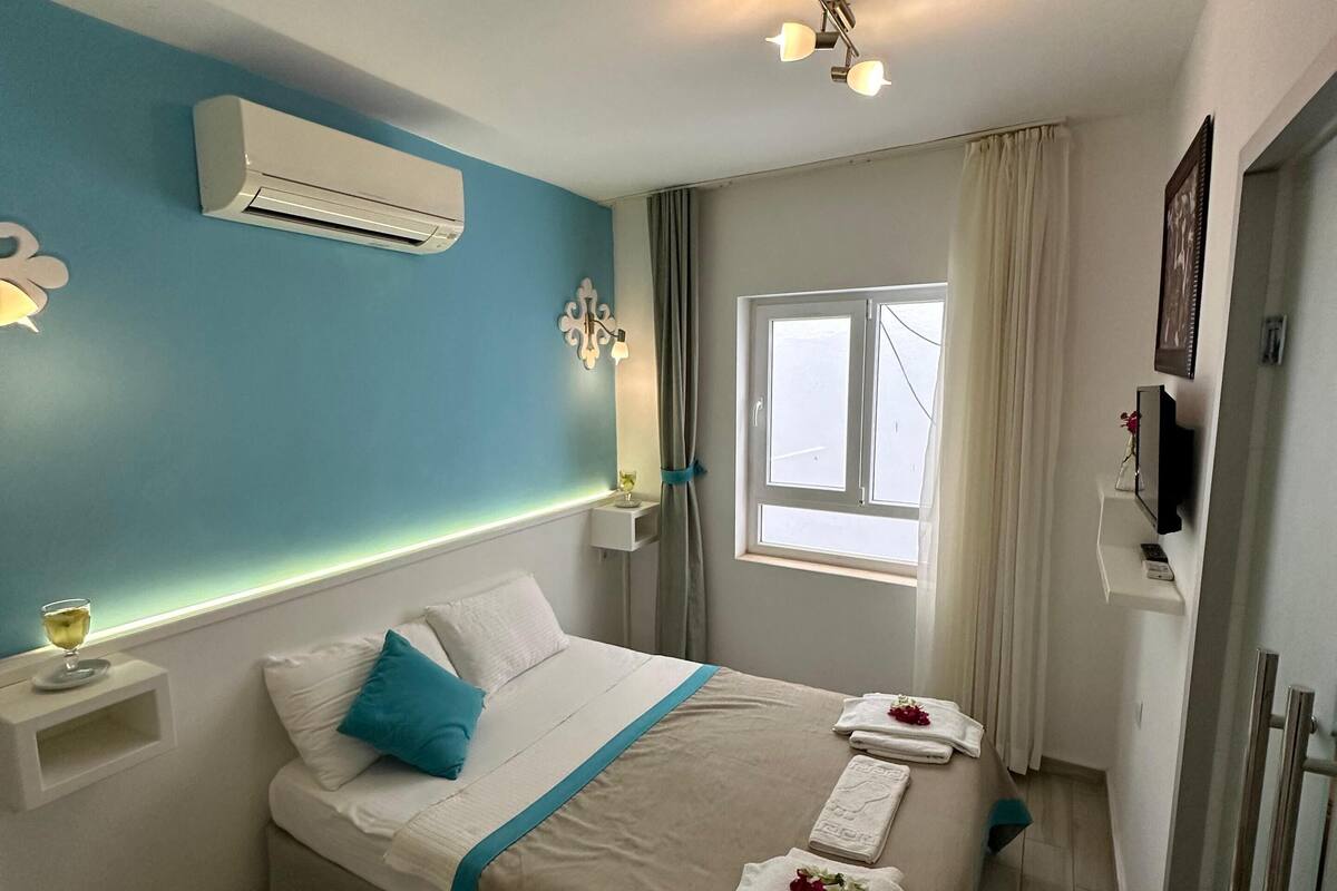 Une chambre d’hôtel avec un lit, des tables de chevet, une télévision et une fenêtre.