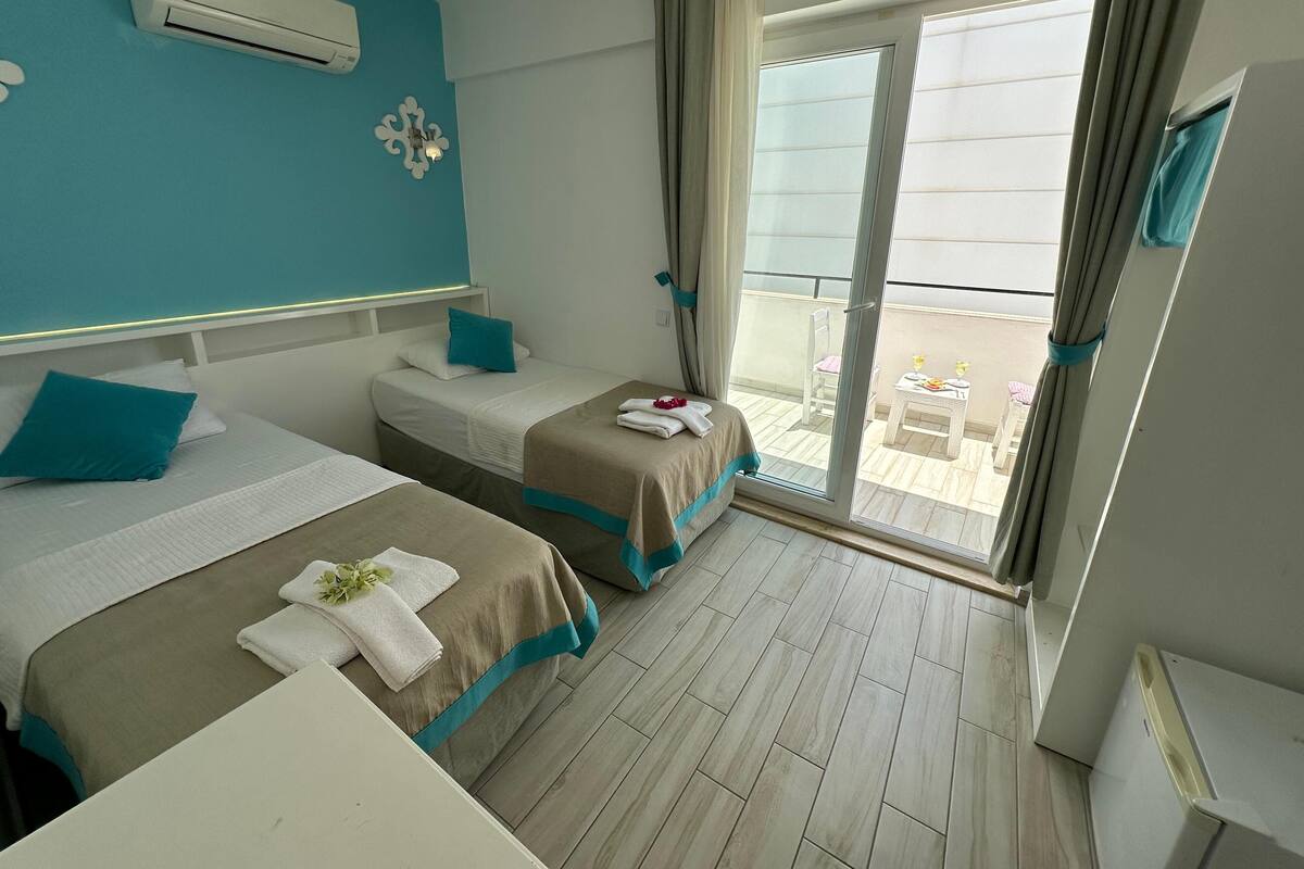 Une chambre d’hôtel avec deux lits, un balcon offrant une vue agréable et une petite table avec des serviettes.