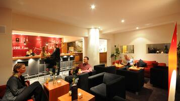 A hotel lobby with a bar area, seating arrangements, and a modern interior design.