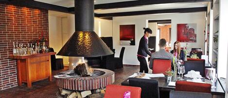 Un restaurante con pared de ladrillo, una chimenea grande y una zona de bar.