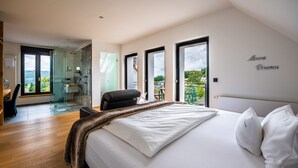 Un dormitorio moderno con una cama grande, cabina de ducha de vidrio y vistas al exterior.