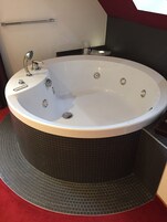 Un baño moderno con una bañera independiente, un perchero y un vaso de agua sobre la encimera.