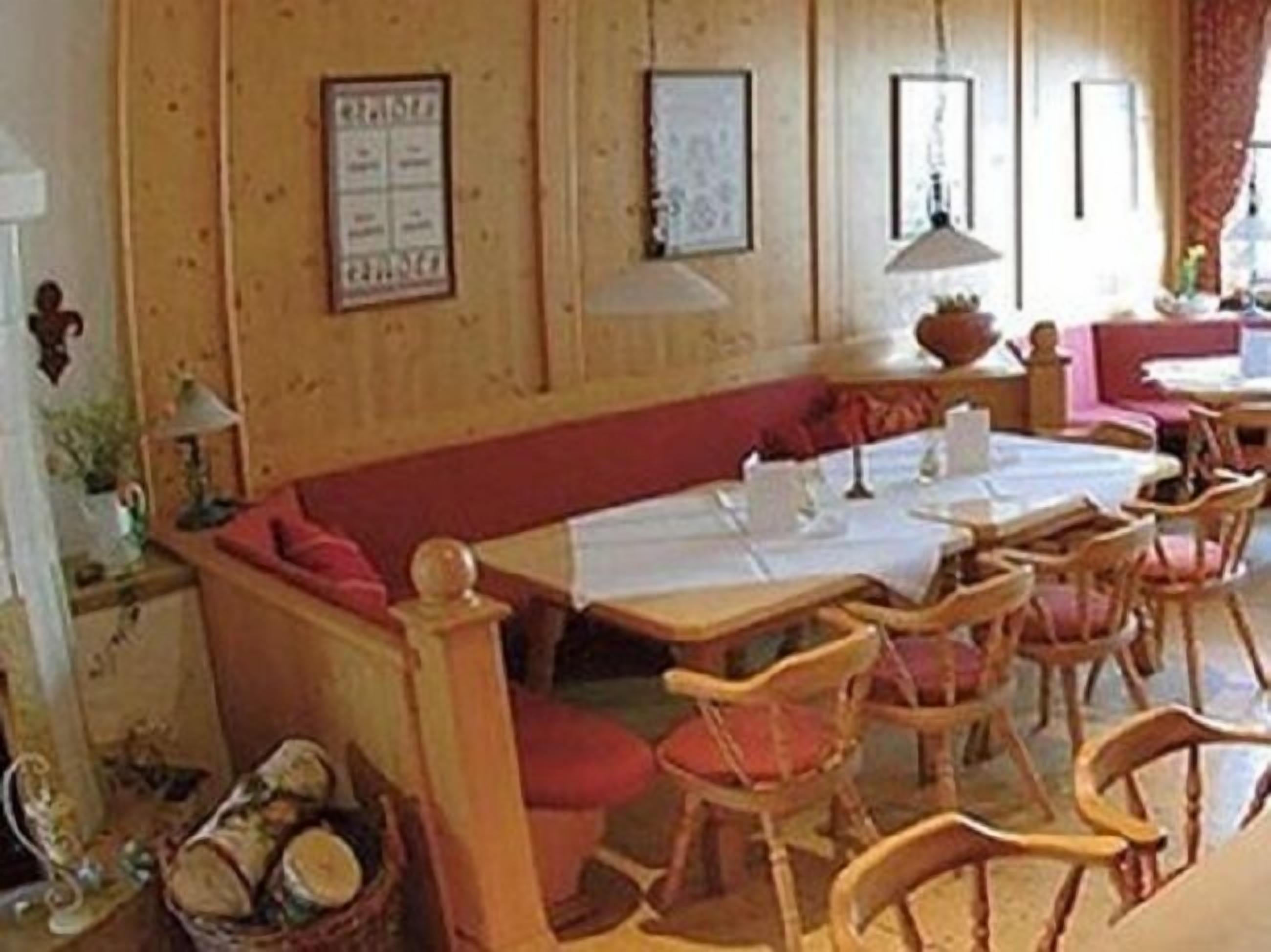 Un comedor acogedor con paredes de madera, un banco con cojines rojos y varias mesas con sillas.